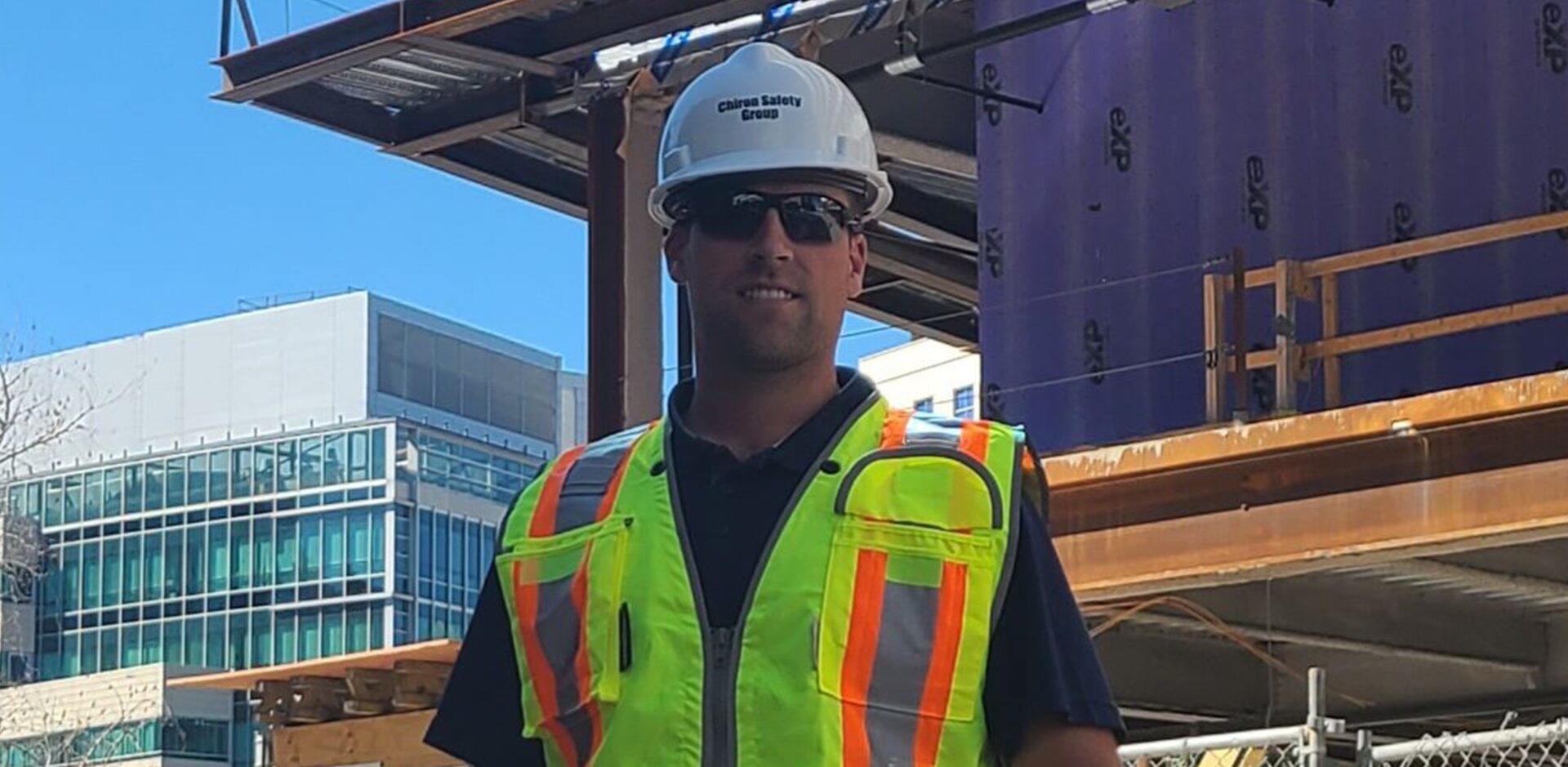 A man in hard hat and safety vest standing on construction site.